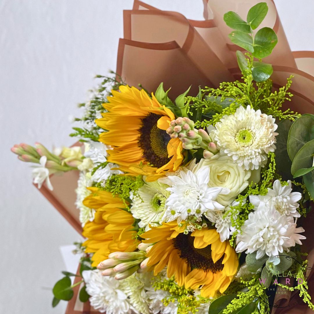 Bouquet of sunflowers and white flowers with a brown paper wrap on a light background