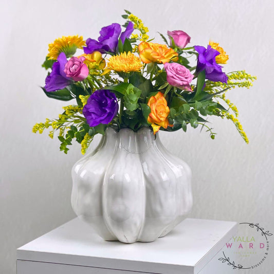 white textured vase with colorful flowers on a white surface against a light gray background.