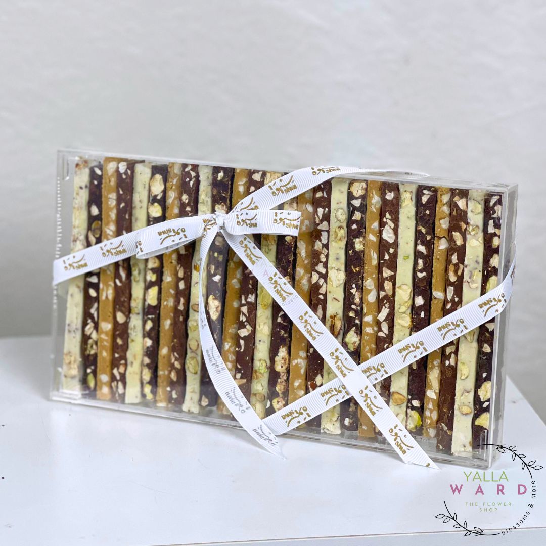 Box of chocolate-covered pretzel rods with a decorative ribbon on a white background