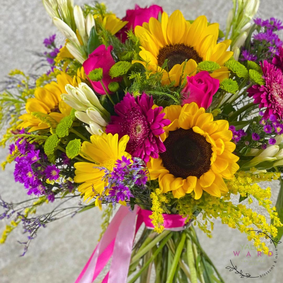 Bouquet of sunflowers, pink and white flowers with a pink ribbon on a light background.