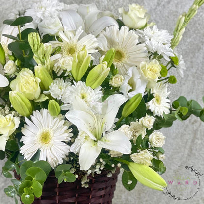 Bouquet of white and green flowers in a basket on a light gray background