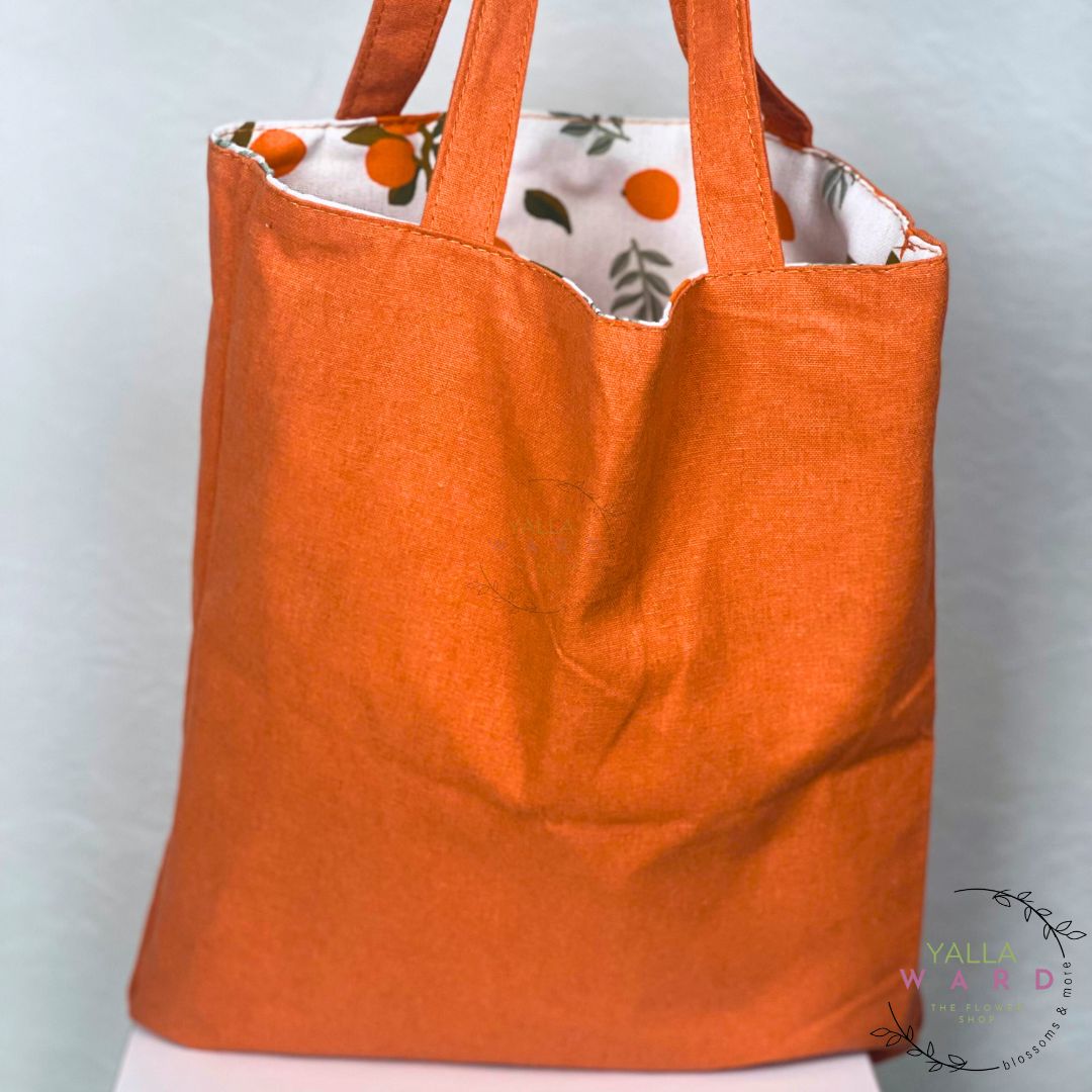 Orange tote bag with floral interior on a light gray background