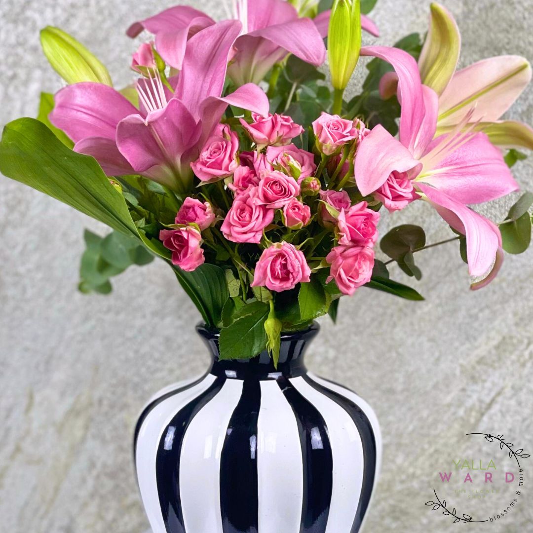 Black and white striped vase with pink flowers on a light background