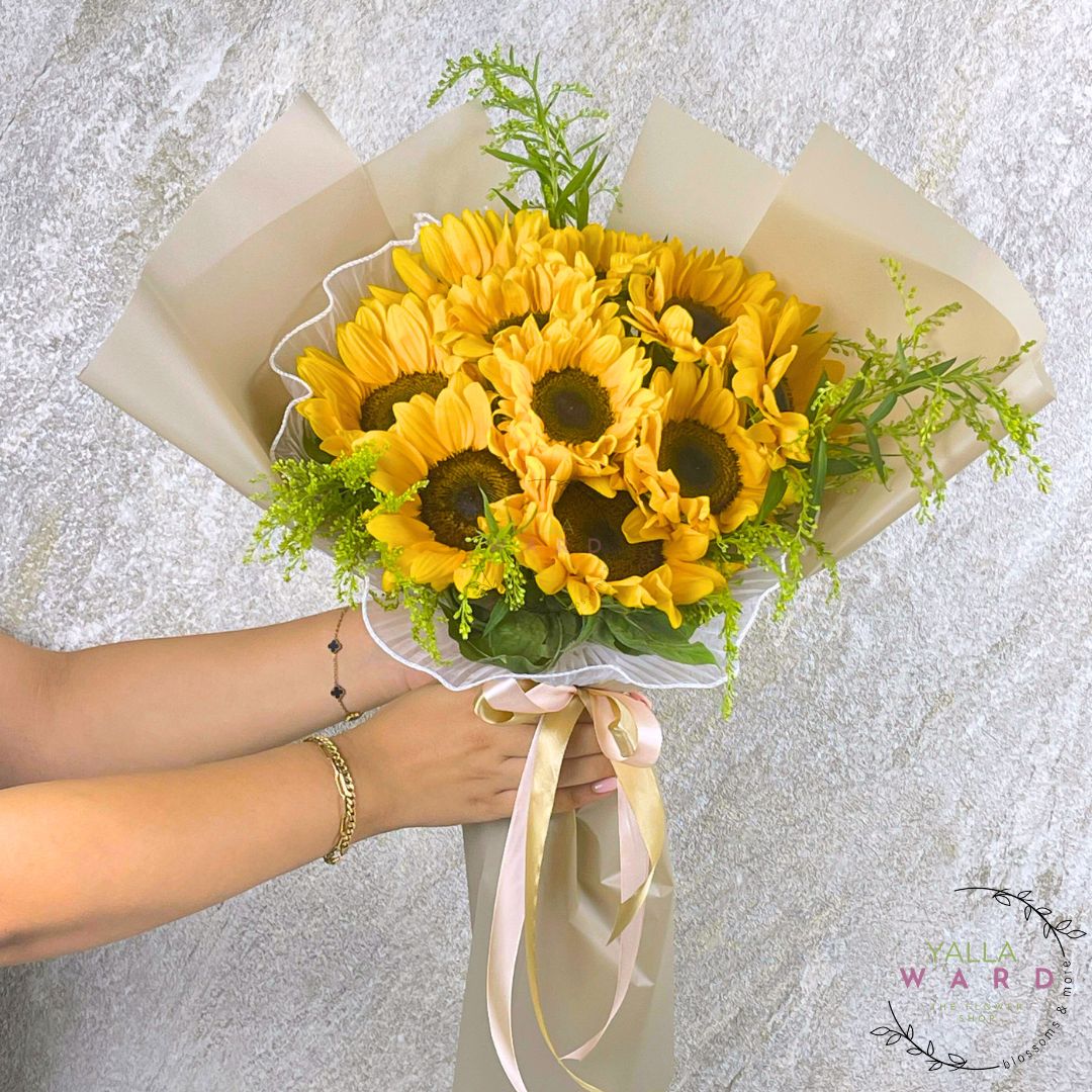 Bouquet of sunflowers held by a person against a textured gray background