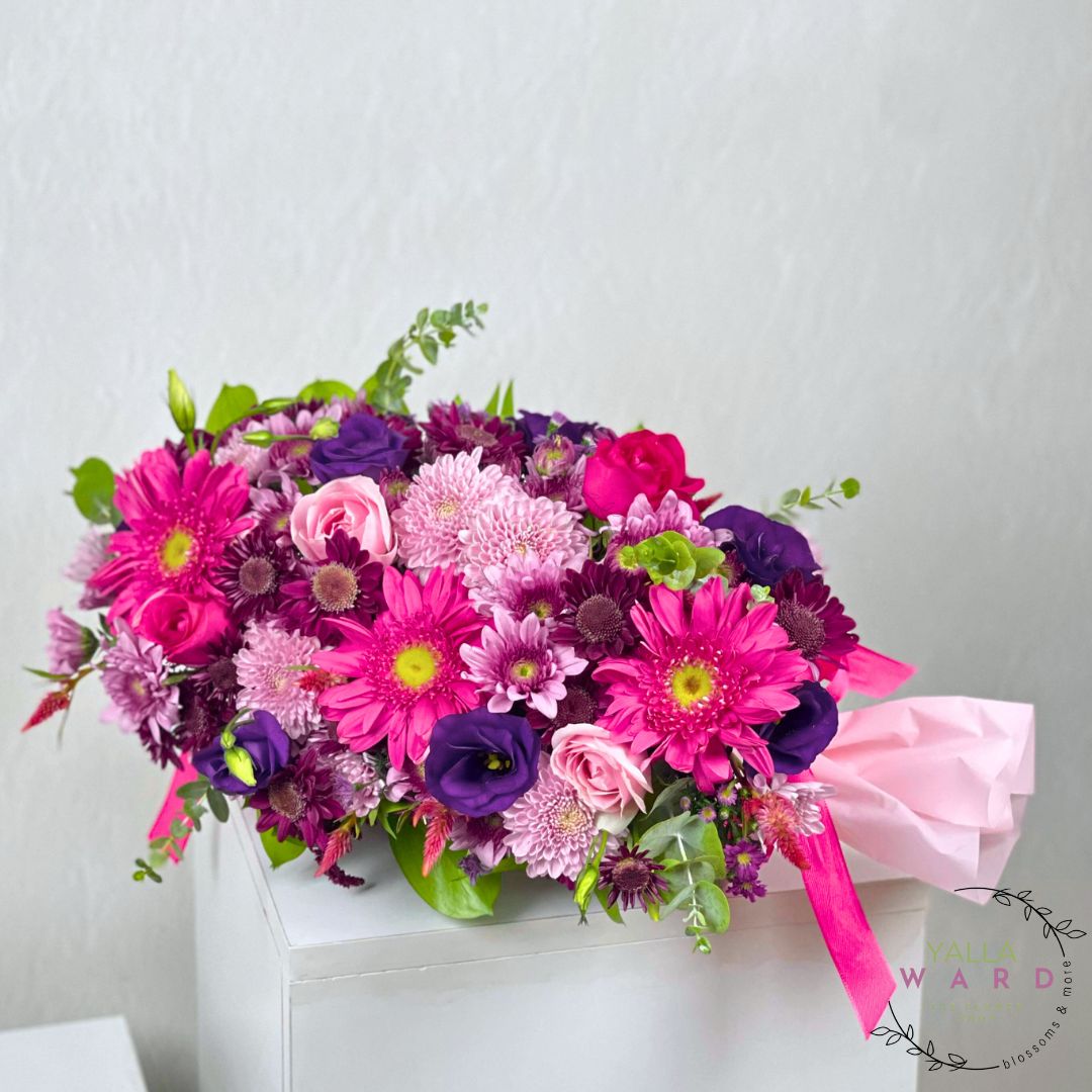 Bouquet of pink and purple flowers in a white box on a light gray background
