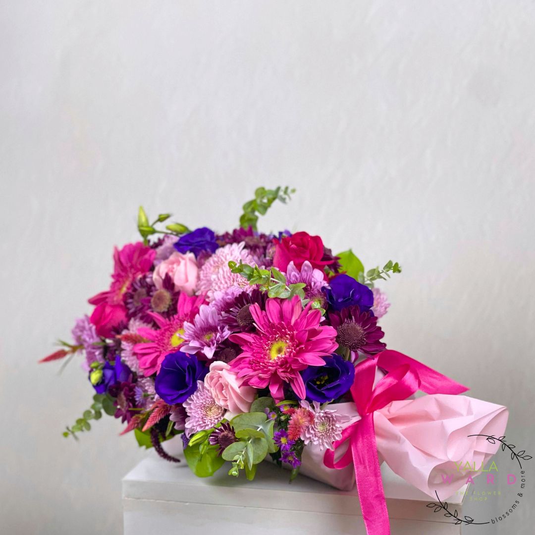 Bouquet of colorful flowers with a pink ribbon on a white surface