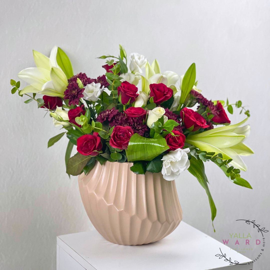 Floral arrangement in a beige vase on a white surface with a light gray background