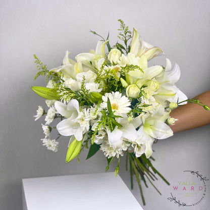 Bouquet of white and green flowers held by a person against a gray background