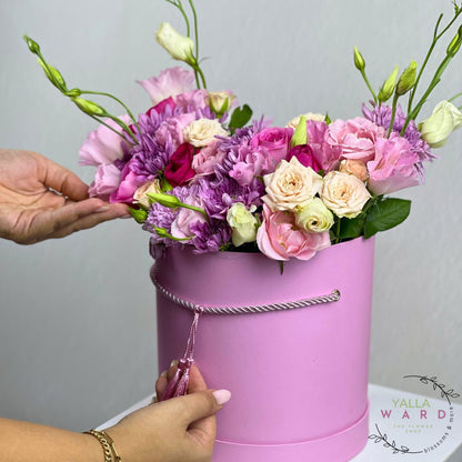 Pink flower box with a hand holding it against a gray background, featuring the brand 'Yalla Ward'.