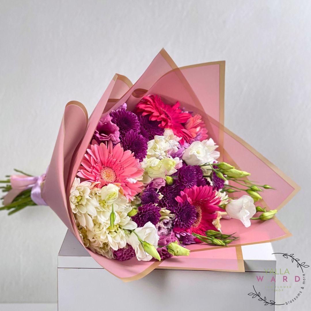 Bouquet of pink flowers wrapped in pink paper on a white surface