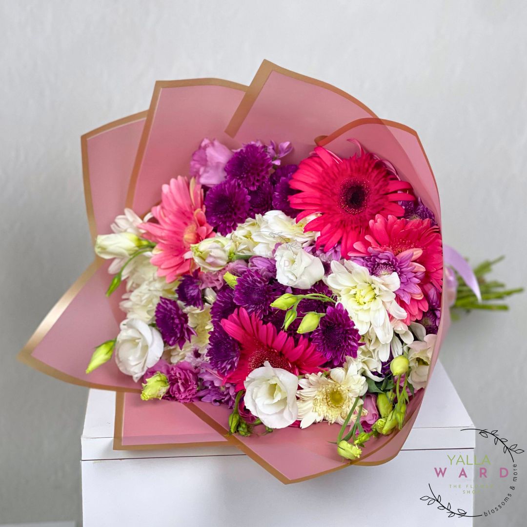 Bouquet of flowers in a pink and gold container on a white background
