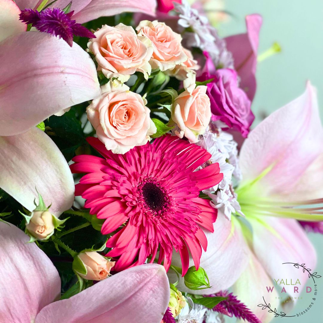 Bouquet of flowers with pink and purple colors, featuring a prominent pink gerbera daisy.