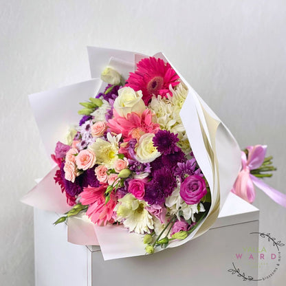 Bouquet of pink and white flowers wrapped in white paper on a light gray background