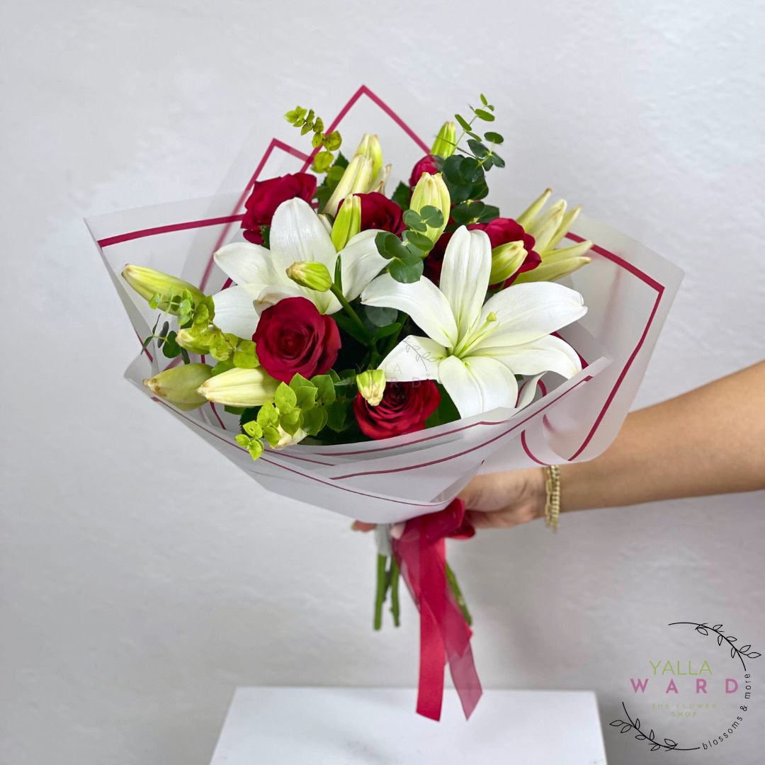 Bouquet of red roses and white lilies held by a hand against a light gray background, with 'Yalla Ward' branding.