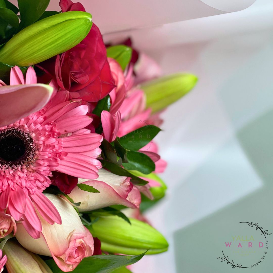Bouquet of pink and red flowers with green leaves on a blurred background