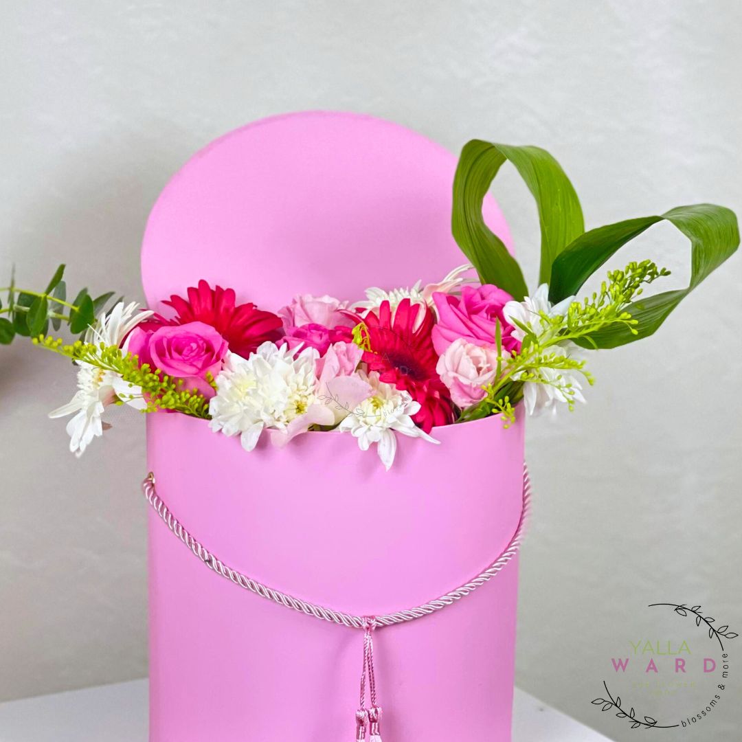 Pink box with flowers and a necklace on a light gray background