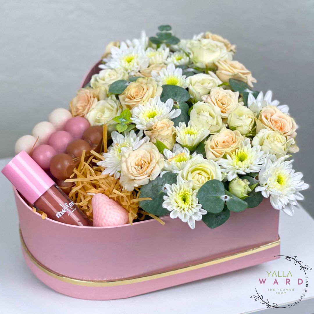 Pink heart-shaped box filled with flowers and lip products 