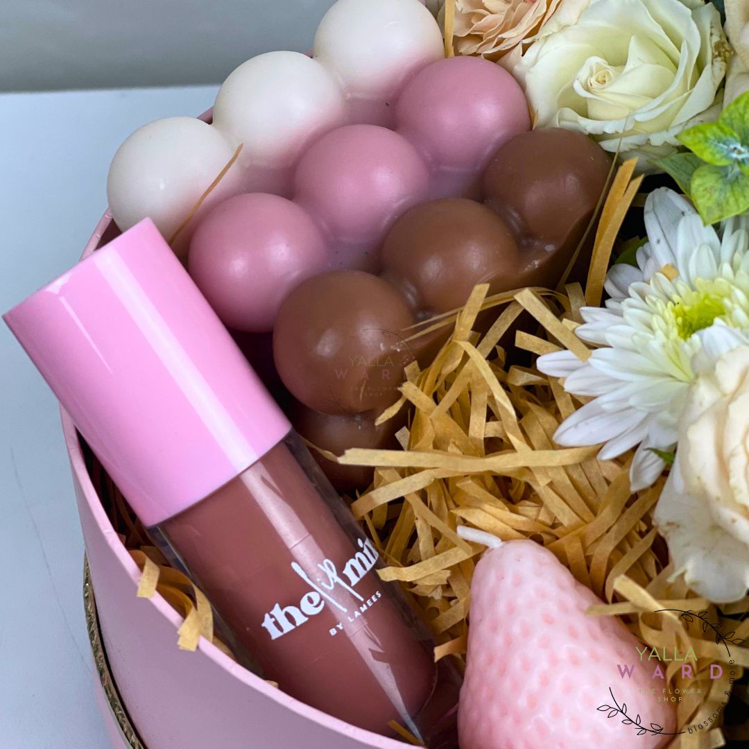 Lip gloss with pink cap and visible brand name in a decorative box with flowers