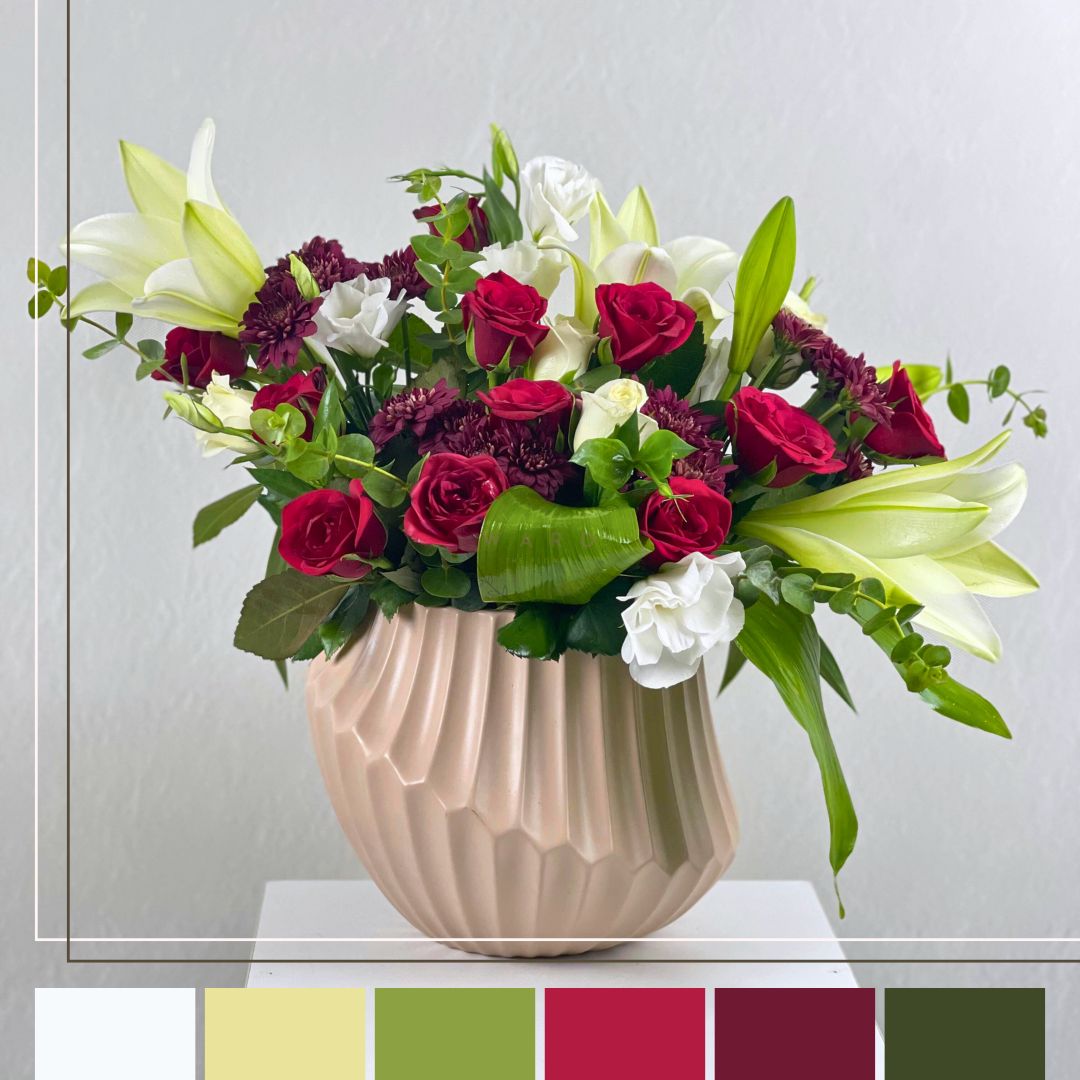 red and whie  flower arrangement in a beige pot  on a white surface with a light gray background.