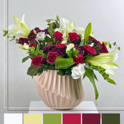 red and whie  flower arrangement in a beige pot  on a white surface with a light gray background.
