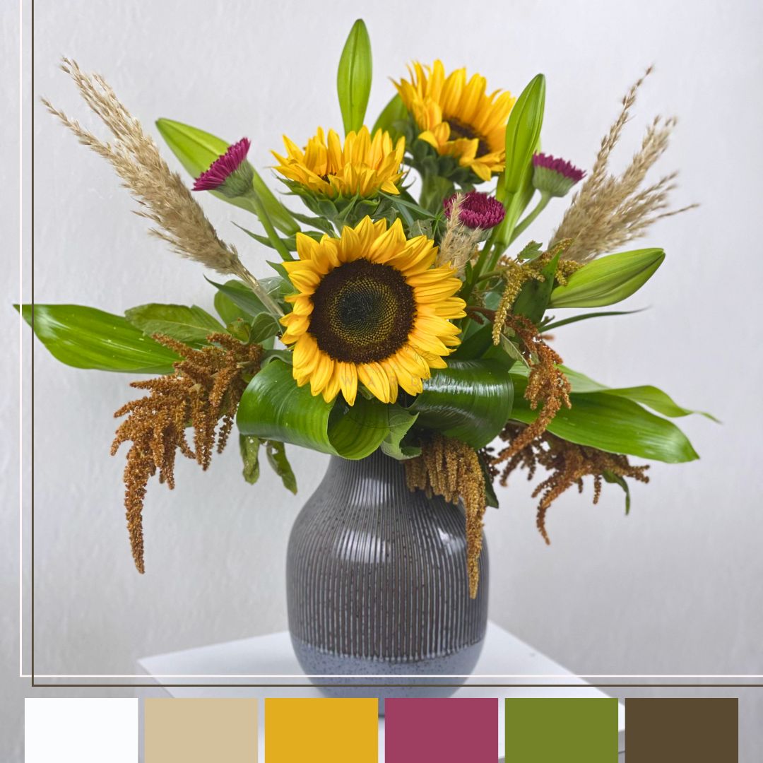 sunflowers and greenery in a gray vase on a white surface with a light gray background.