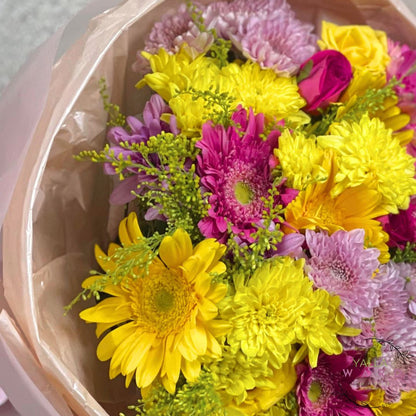 Bouquet of yellow and pink flowers in a clear plastic wrap.