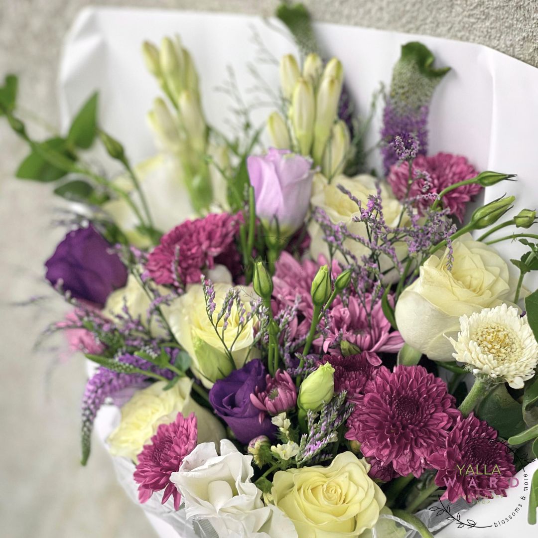 Bouquet of flowers with purple, yellow, and white flowers on a light background