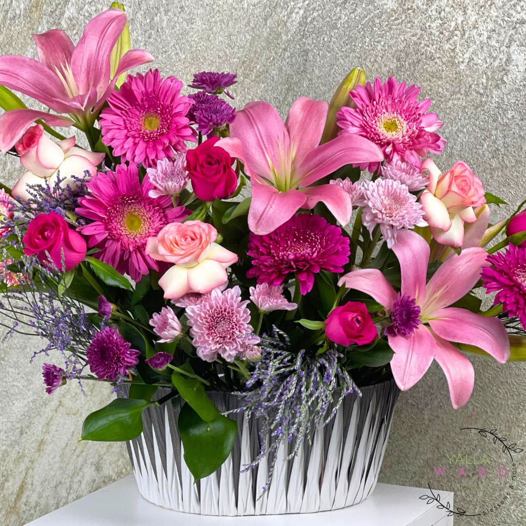 pink and purple flowers in a white container against a neutral background