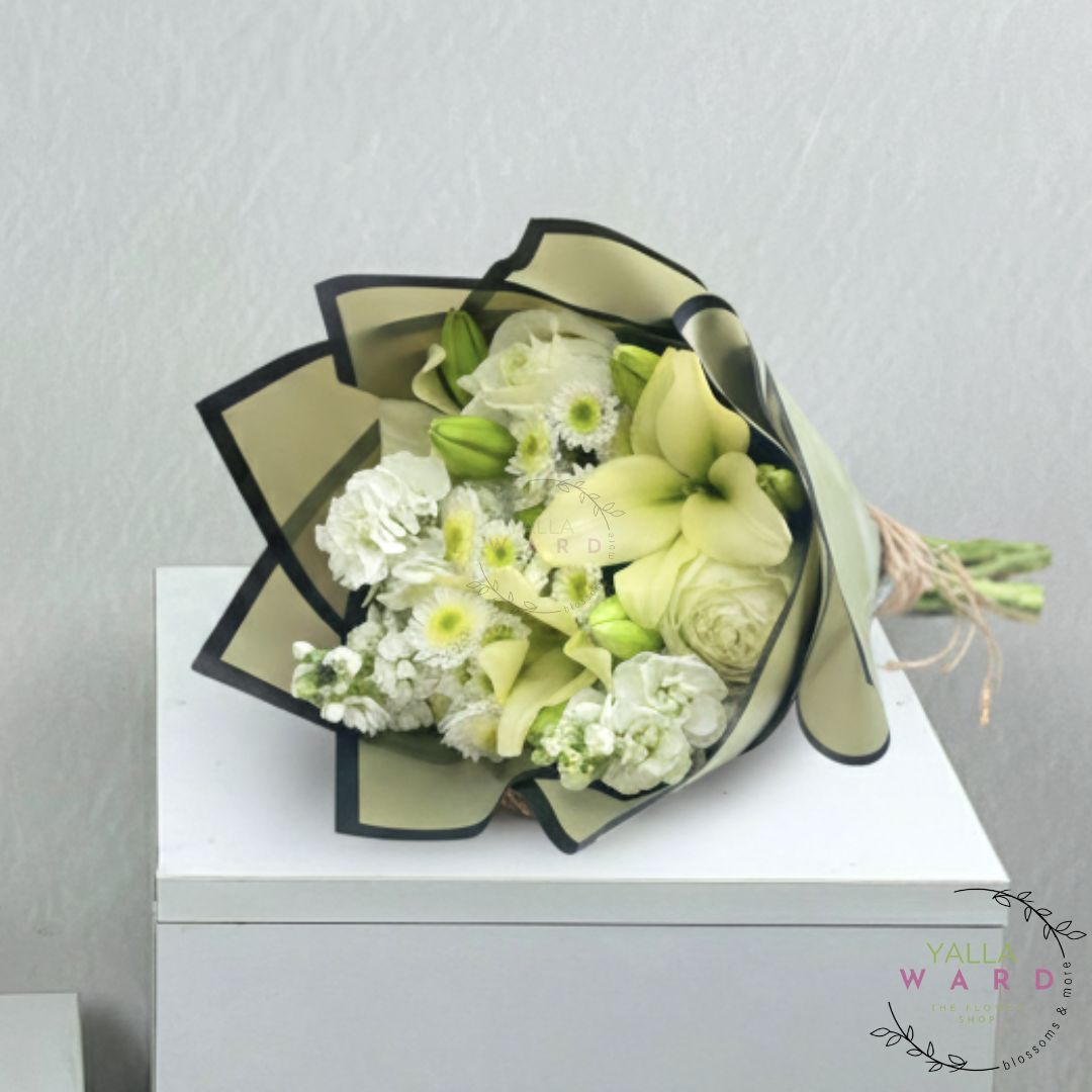 Bouquet of white and green flowers wrapped in black paper on a white surface with a light gray background.