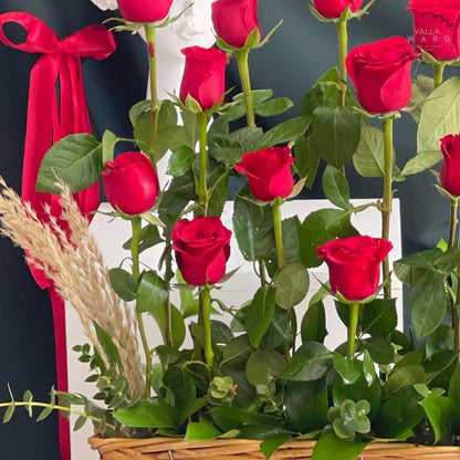 Basket of red roses with a red ribbon against a dark background
