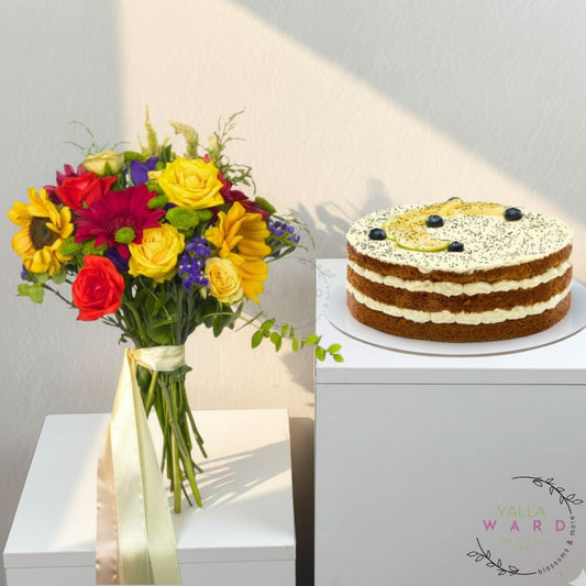 Colorful bouquet of flowers and a layered cake on a white surface with a gray background.
