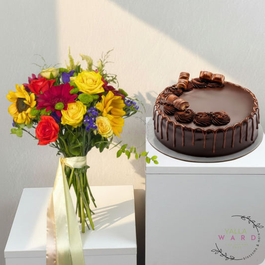 Bouquet of colorful flowers and a chocolate cake on a white surface with a brand logo.